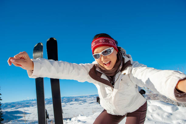 Young woman skiing at ski resort in the Alps. She is skiing fast on a wide ski slope.Beautiful, sunny winter day.Shot with Canon R5