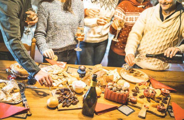 side view of friends group tasting christmas sweets food and having fun at home drinking champagne sparkling wine - winter holidays concept with people enjoying time eating together - warm filter - italian appetizer imagens e fotografias de stock