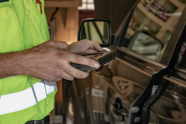 istock Mobile automotive technician checks out a car with his computer device with the clients garage reflecting in the car he is working on 1064331132