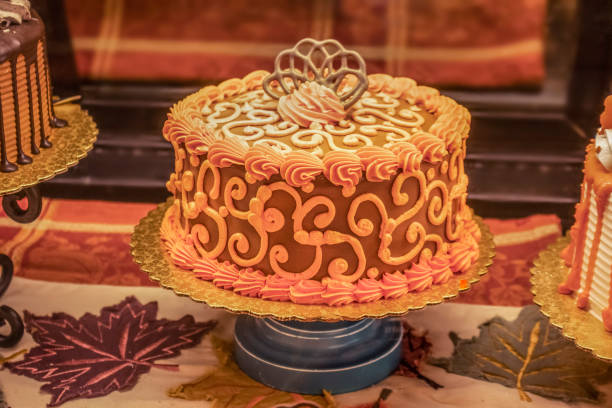 Fall themed decorated cakes displayed for sale on an Autumn leaf runner- oranges and golds