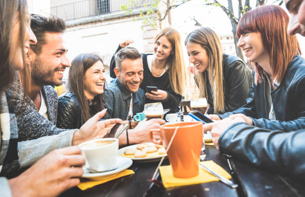 istock Happy friends talking and having fun with mobile smart phones at restaurant drinking cappuccino and hot tea - Young people together at cafeteria - Friendship concept with men and women at coffee bar 1064332232