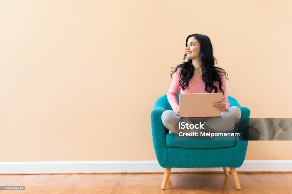 Young woman using her laptop Young woman using her laptop on a blue chair Backgrounds Stock Photo