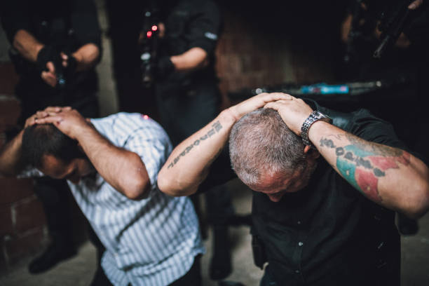 swat arresting gangster in warehouse - police helmet imagens e fotografias de stock