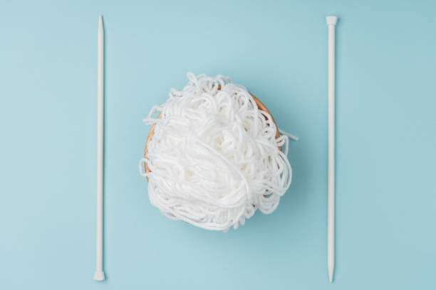 istock top view of white yarn in bowl and knitting needles on blue backdrop 1064344572