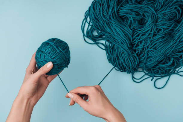 istock partial view of woman rolling yarn ball on blue background 1064344646
