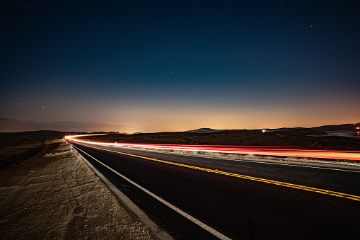 Desert road in California, USA at night with lights of passing cars.