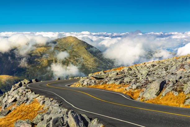 Winding road descending from Mount Washington, NH Winding road descending from Mount Washington, NH on a sunny autumn afternoon. Mount Jefferson peak stands above a thick layer of fluffy clouds. white mountains new hampshire stock pictures, royalty-free photos & images