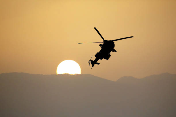 istock Silhouette of a flying helicopter against the setting sun 1064406002