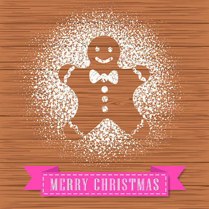 Decorate a gingerbread man shape with powdered sugar on hardwood background for Christmas