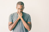 istock Calm spiritual handsome African guy praying with closed eyes 1064433774