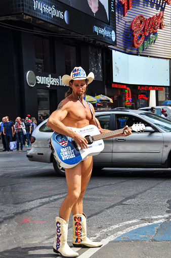 New York, USA - September 28, 2014: Cowboy is playing gitar in Times Square in New York. Times Square is a major commercial intersection, tourist destination, entertainment center and neighborhood in the Midtown Manhattan section of New York City at the junction of Broadway and Seventh Avenue
