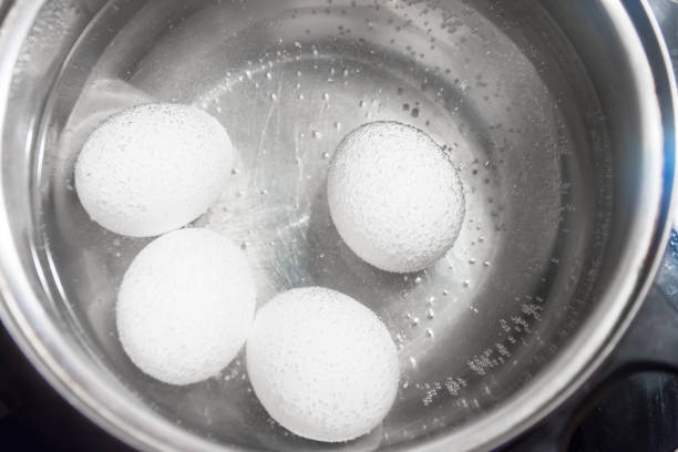 Cooking white chicken eggs in a saucepan.