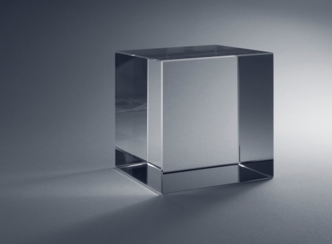 studio photography of a solid glass cube in grey back