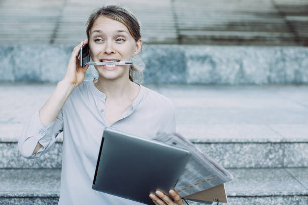 istock Multitasking businesswoman talking on phone with pen in teeth 1064445354
