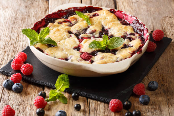 Summer berry cake with raspberry berries, currants and blueberries close-up in a baking dish. horizontal Summer berry cake with raspberry berries, currants and blueberries close-up in a baking dish on a table. horizontal cobbler dessert stock pictures, royalty-free photos & images
