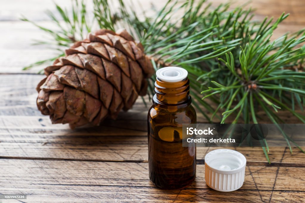 Cedar and spruce essential oil in small glass bottles on wooden background. Selective focus. Essential Oil Stock Photo