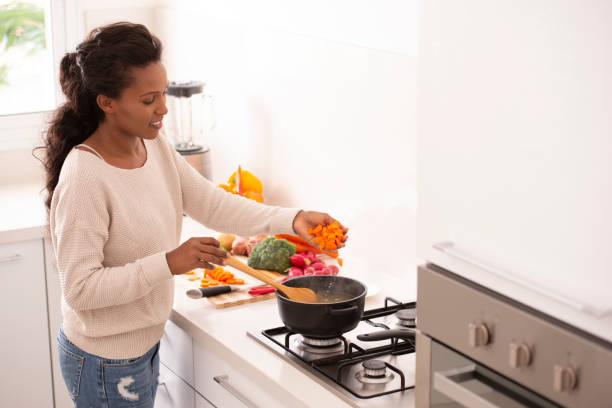 istock Woman preparing soup, adding chopped carrots into the pot. 1064456636