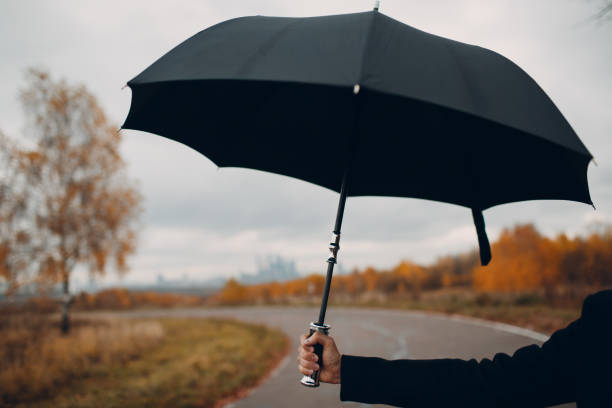 istock Young man in black holding umbrella. 1064458908