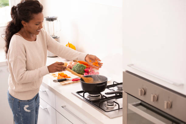 istock Woman preparing soup, adding chopped carrots into the pot. 1064460698