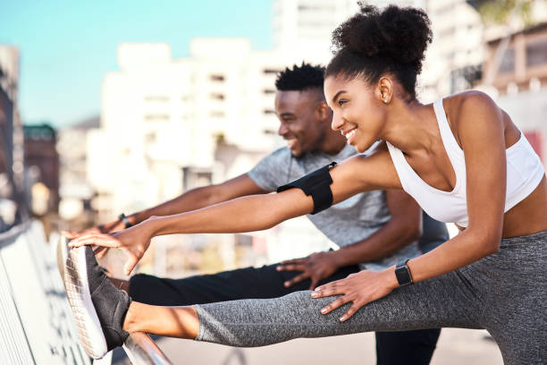 Getting their stretch on Cropped shot of a young couple warming up before their workout in the city warm up exercise stock pictures, royalty-free photos & images