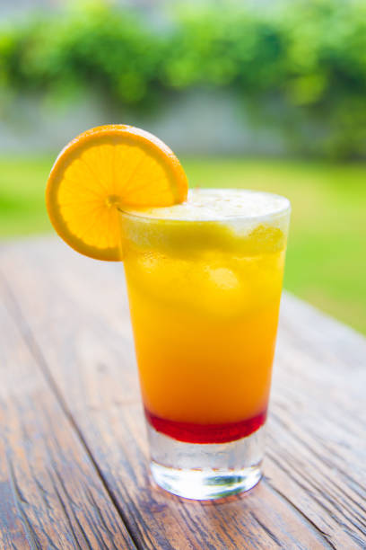 Fresh orange juice in the glass jar on wooden desk with nature background.