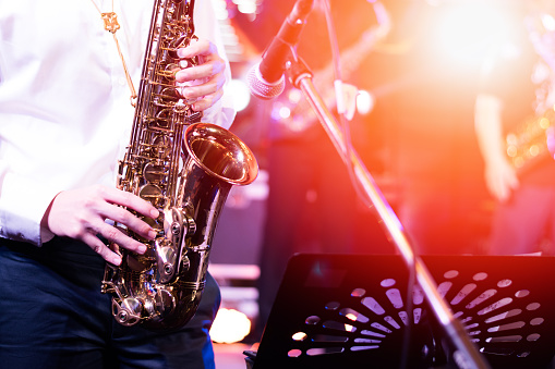 Music, band and saxophone with people in a recording studio, reading sheet music for a performance. Concert, jazz and a musician group playing an instrument for art, creative or sound at a showcase