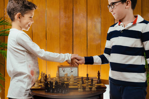 istock School boys shaking hands after a game of chess. 1064481740