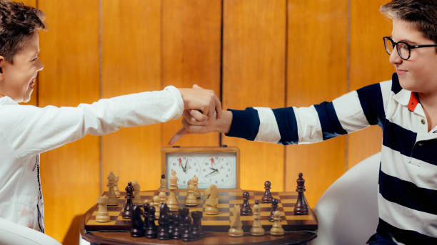 istock School boys shaking hands after a game of chess. 1064481786