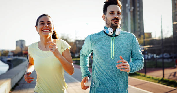 istock Young attractive couple running outside on sunny day 1064483652