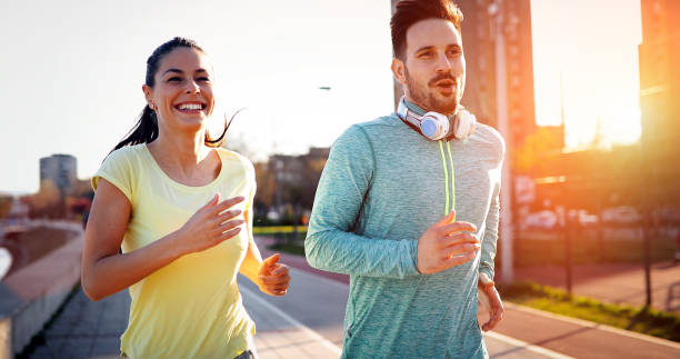 istock Young attractive couple running outside on sunny day 1064483658