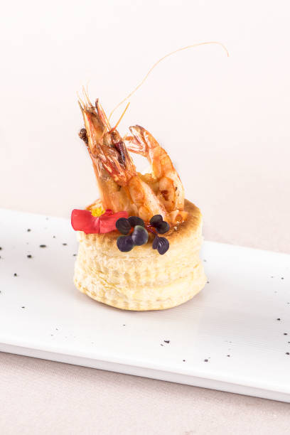 istock Fresh appetizer with shrimp,  on pastry,  decorated with eatable red flower and green leaf,  placed on white plate,  light background,  isolatedFresh appetizer with shrimp,  on pastry,  decorated with eatable red flower and green leaf,  placed on white pl 1064486304