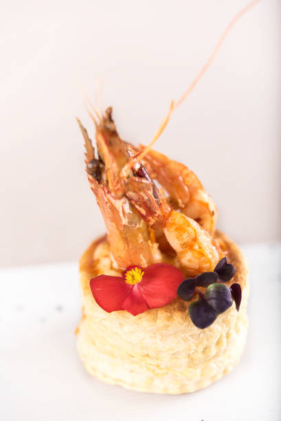 istock Fresh appetizer with shrimp,  on pastry,  decorated with eatable red flower and green leaf,  placed on white plate,  light background,  isolatedFresh appetizer with shrimp,  on pastry,  decorated with eatable red flower and green leaf,  placed on white pl 1064486380