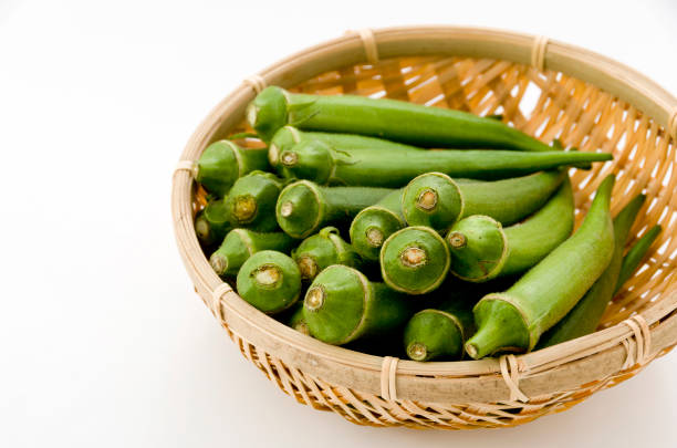 istock resh okra on bamboo sieve isolated white background. 1064494618