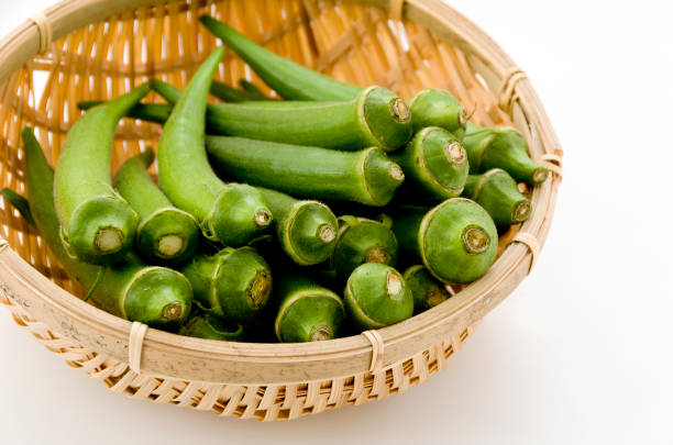 istock resh okra on bamboo sieve isolated white background. 1064495840