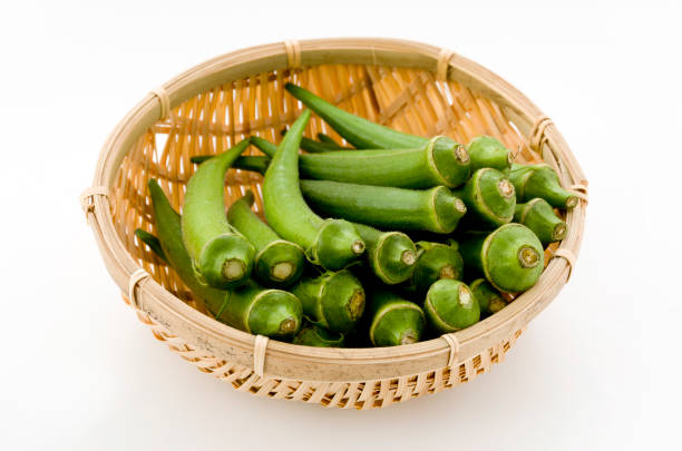 istock resh okra on bamboo sieve isolated white background. 1064495956