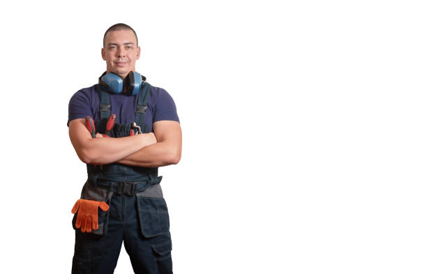 strong male mechanic in blue overal standing with orange gloves, white helmet, ear protection and tools. - auto repair shop adult auto mechanic blue imagens e fotografias de stock