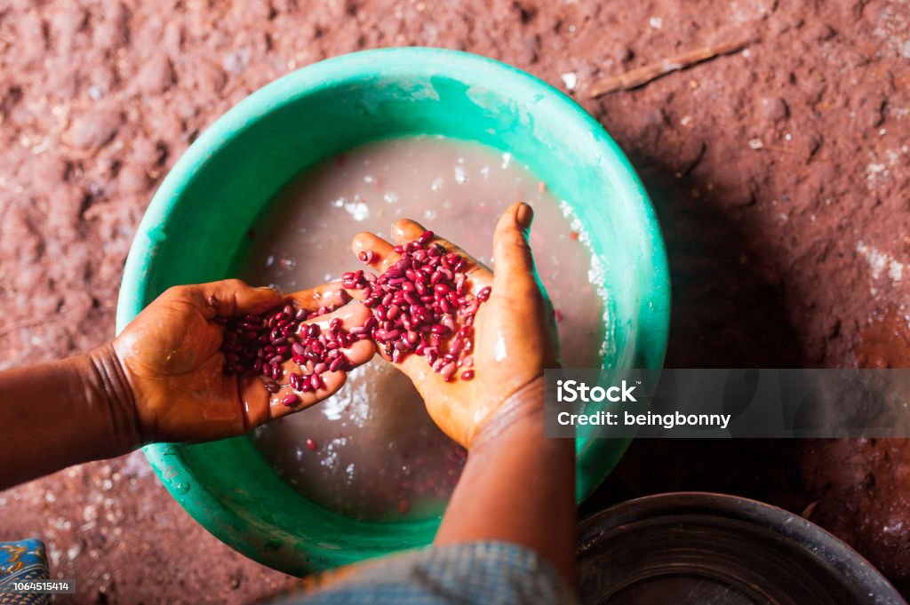 hands of african woman holding red beans view from above in village kitchen while cooking food Africa Stock Photo