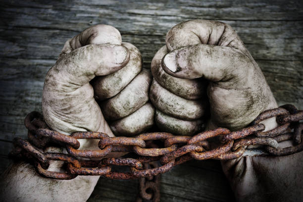 Powerful male hands clenched into fists and chained with old rusty thick chain stock photo