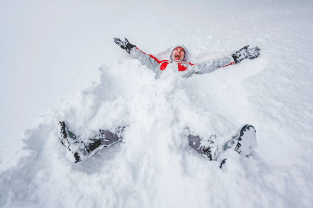 Snow Angel Winter snow joy, man spreading legs and arms, creating snow angel. snow angels stock pictures, royalty-free photos & images