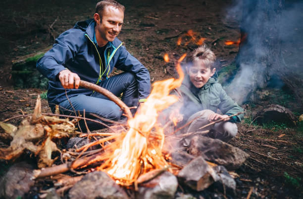 istock Father and son make bonfire in forest. Camping trip at spring or autumn time 1064535920