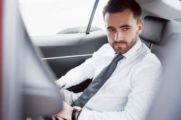 istock A young businessman arranges his affairs with a notepad while sitting in the car's back 1064538340