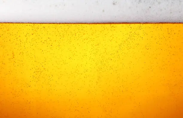 Photo of Close up background of beer with bubbles in glass