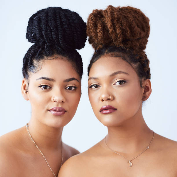 Getting their glow on Studio shot of two beautiful young women posing against a grey background braided buns stock pictures, royalty-free photos & images