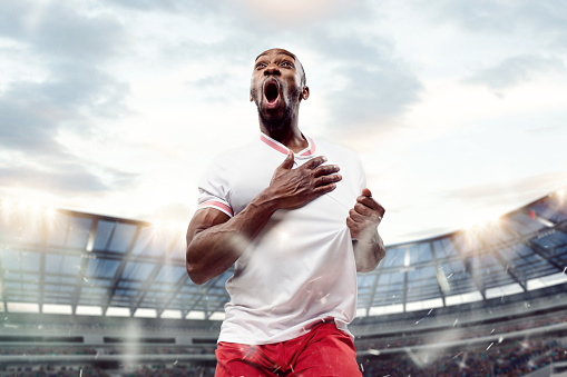 The football african player in motion on the field of stadium at day. The professional football, soccer player and human emotions concept. The win winner , victory concept