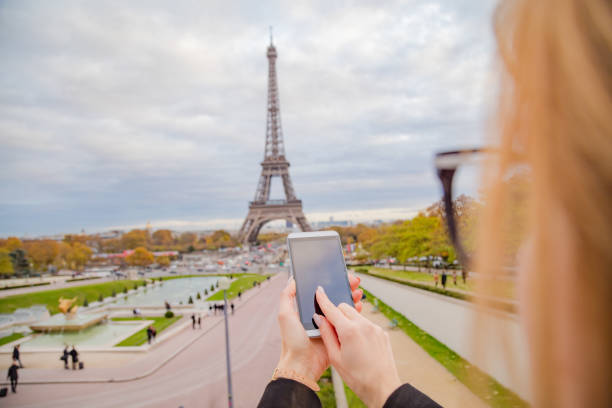 istock Girl using cellphone with Paris city background and Eiffel tower. 1064546690