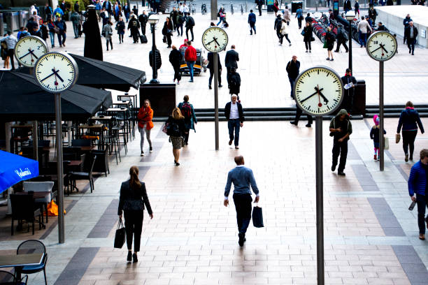 Canary Wharf business people, London Business people walking in Canary Wharf by the iconic clock installation on Reuters plaza, London's financial district canary wharf photos stock pictures, royalty-free photos & images