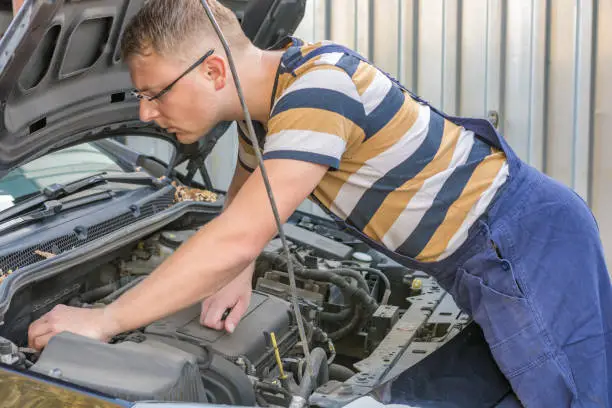 Photo of Mechanic looks at the engine compartment of a car