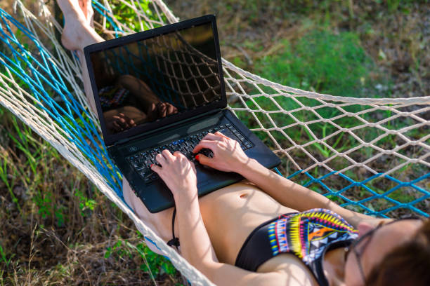 istock Young woman lying in a hammock and looking to a laptop. 1064550904