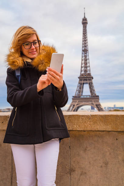 istock Girl using cellphone with Paris city background and Eiffel tower. 1064552382