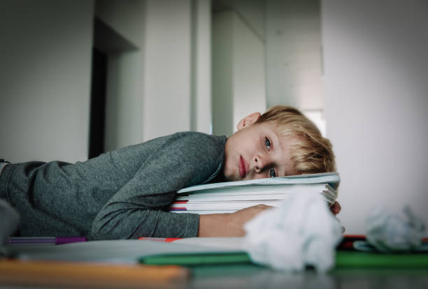 istock little boy tired stressed of reading, doing homework 1064555696